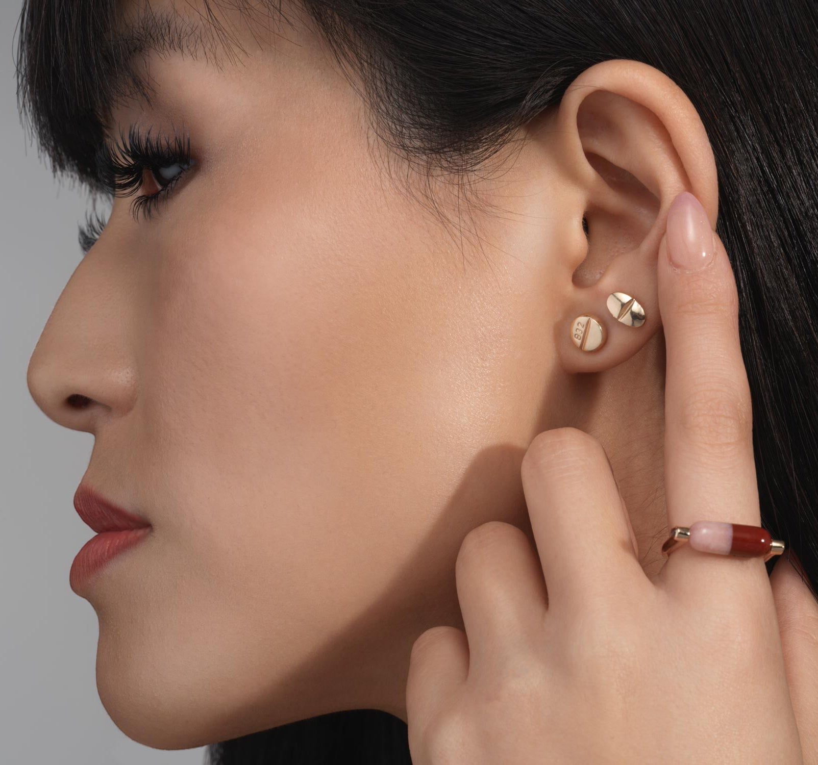 Mad Fine mismatched 14k gold stud earrings inspired by prescription pills, one oval with a line, the other round with "832" engraving.